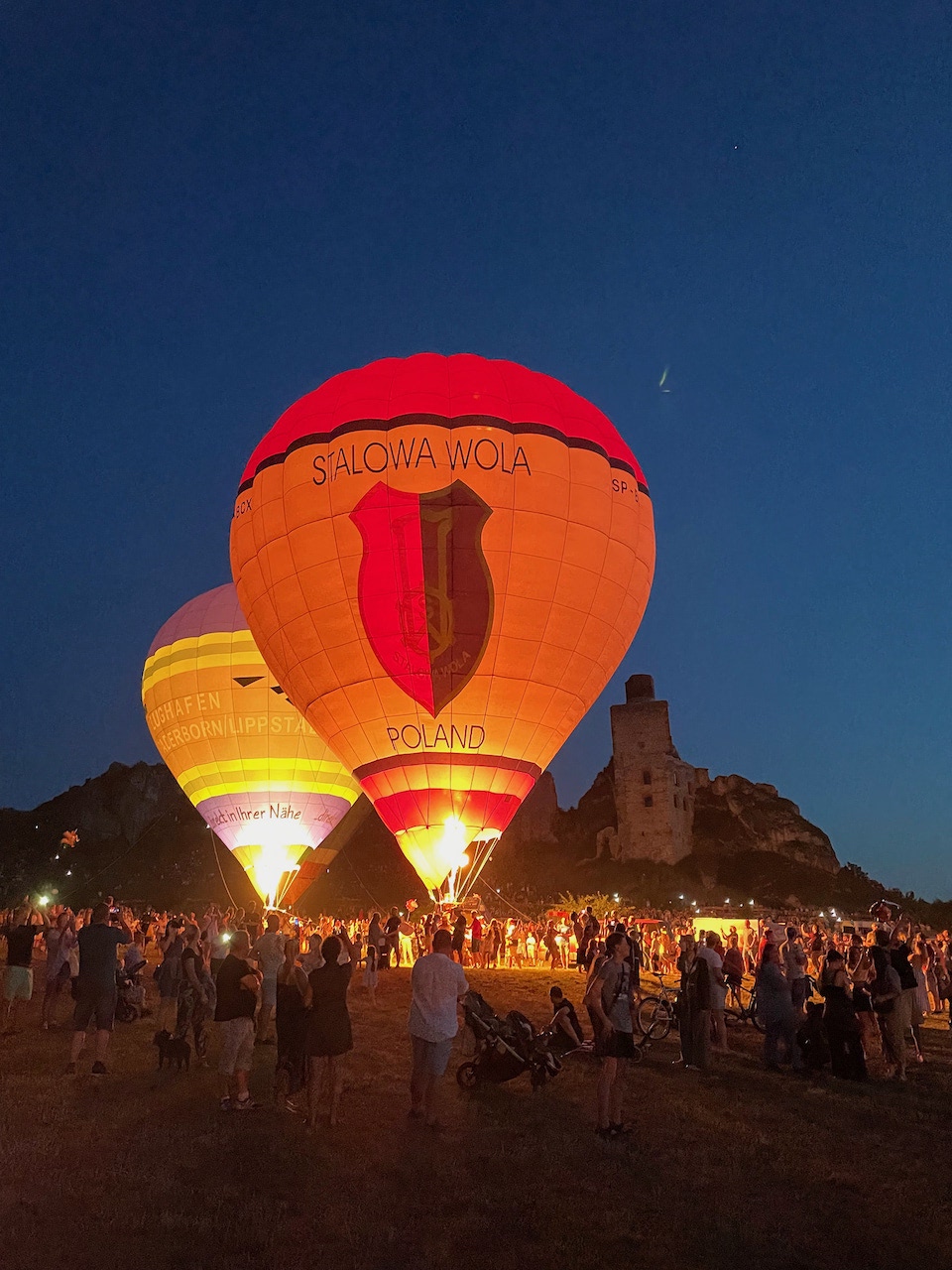 Hot air balloons being launched in late evening in front of a castle